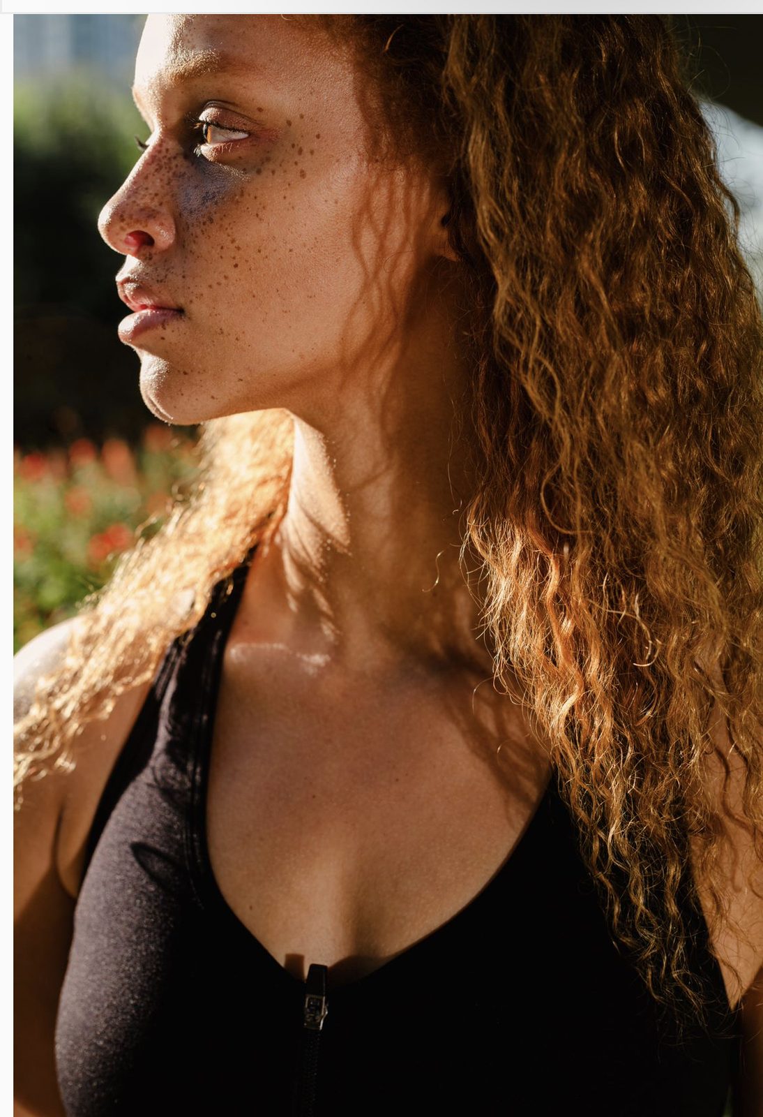 Juliana in warm sunlight, curly hair catching the light, wearing a black athletic top